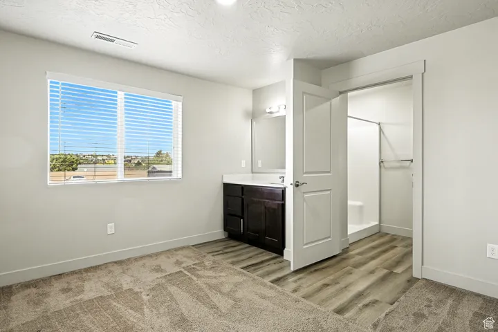 Bathroom featuring a shower stall, vanity, a textured ceiling, and light wood finished floors