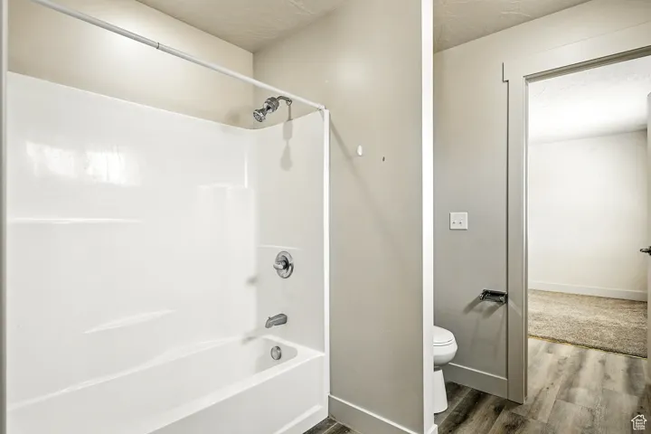 Full bathroom featuring bathing tub / shower combination, wood finished floors, and a textured ceiling