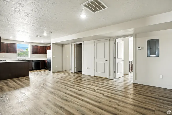 Unfurnished living room featuring electric panel, a textured ceiling, and light wood-type flooring