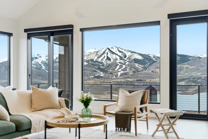 Spacious interior featuring expansive floor-to-ceiling windows, soaring vaulted ceilings, and direct outdoor access to a balcony