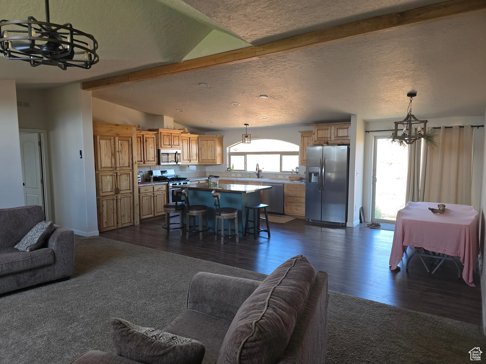 Living room with a chandelier, a textured ceiling, dark wood finished floors, and dark colored carpet
