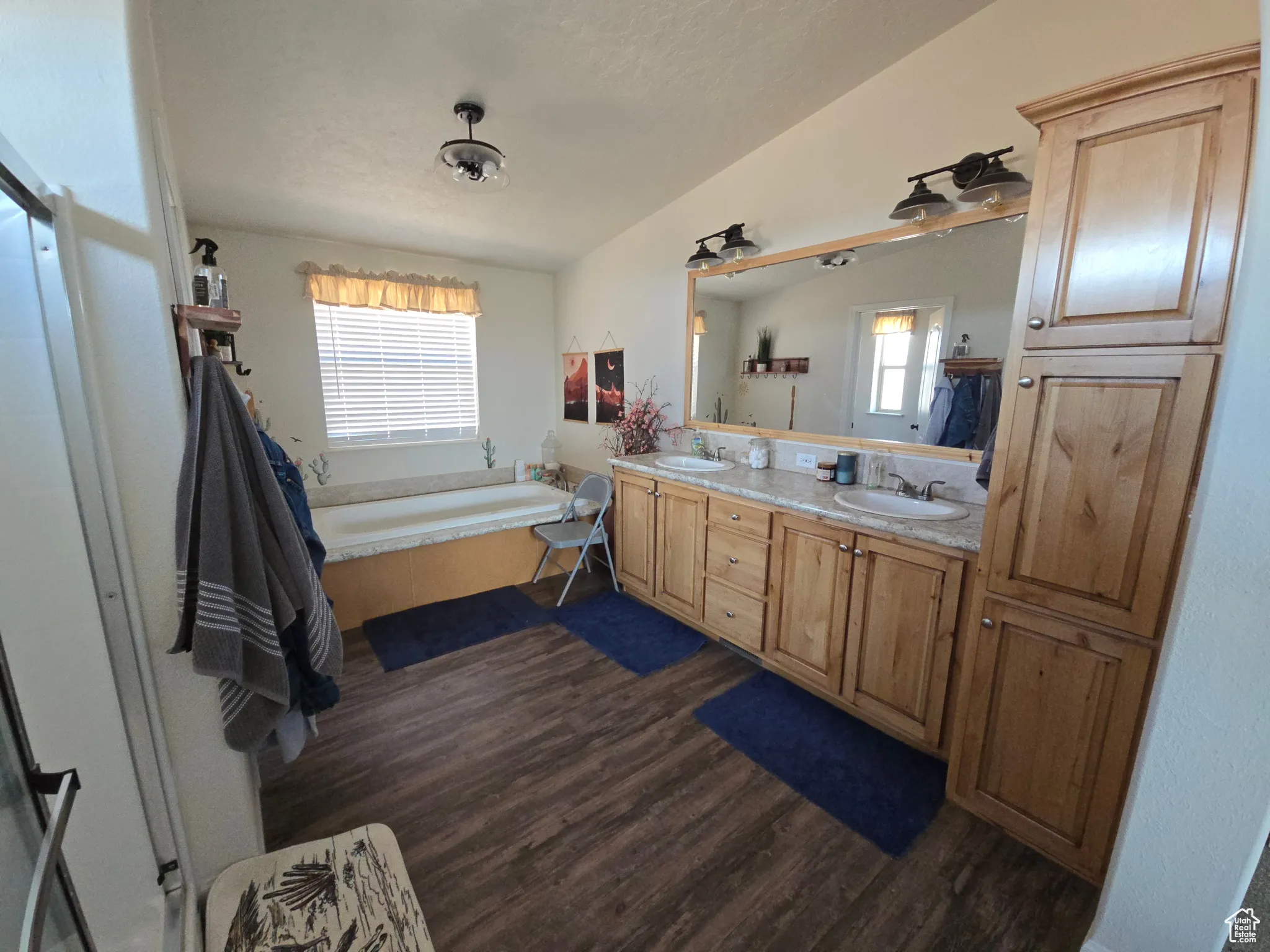 Full bathroom with double vanity, a bath, and dark wood finished floors