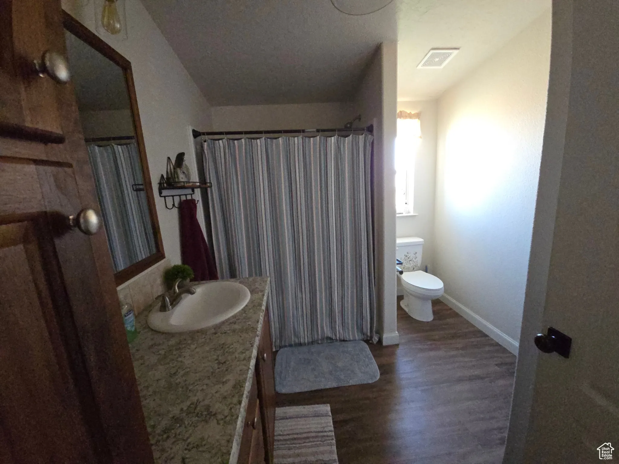 Full bath featuring dark wood finished floors, vanity, and curtained shower