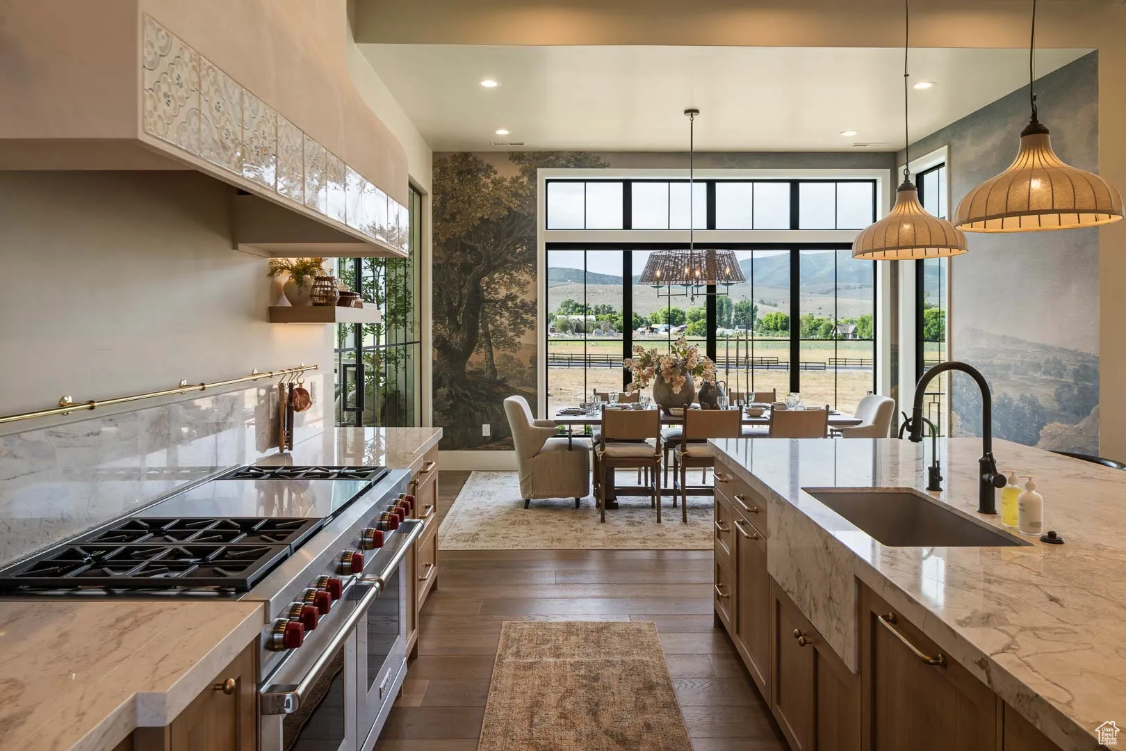 Kitchen featuring double oven range, a mountain view, decorative light fixtures, light stone counters, and brown cabinets