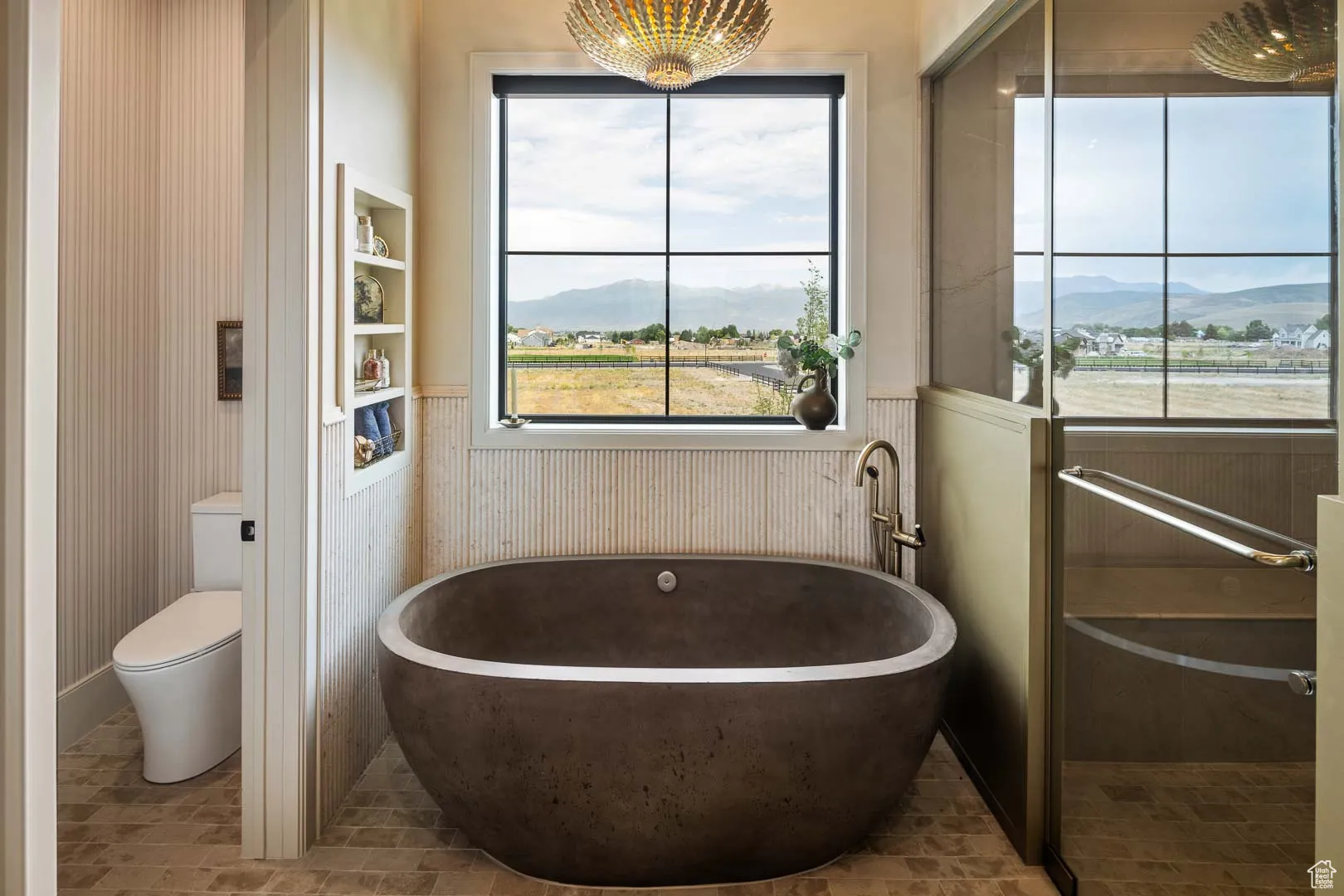Bathroom with a mountain view, a soaking tub, and a wainscoted wall