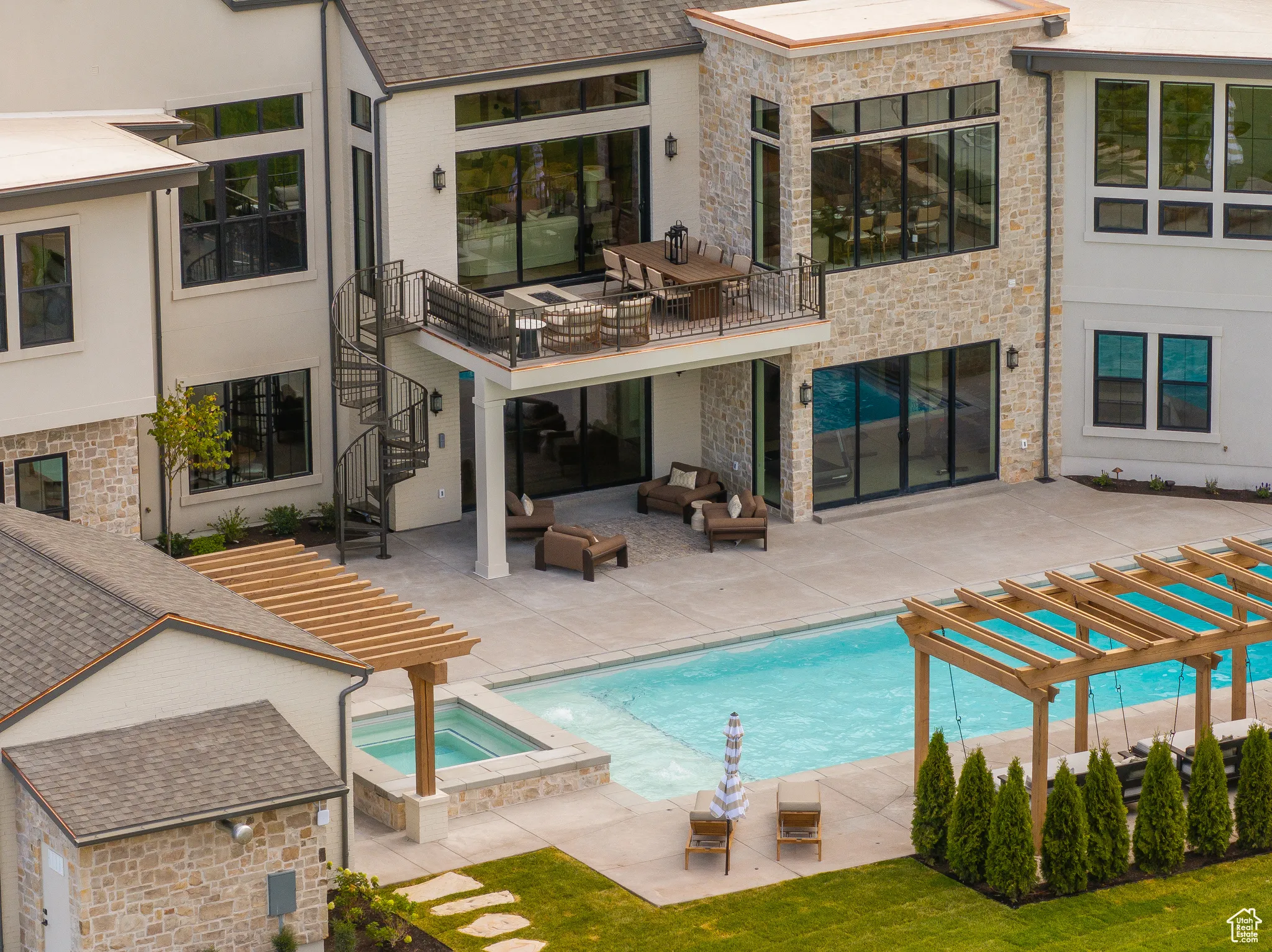 Back of house featuring a patio area, a pool with connected hot tub, stairs, a balcony, and an outdoor living space