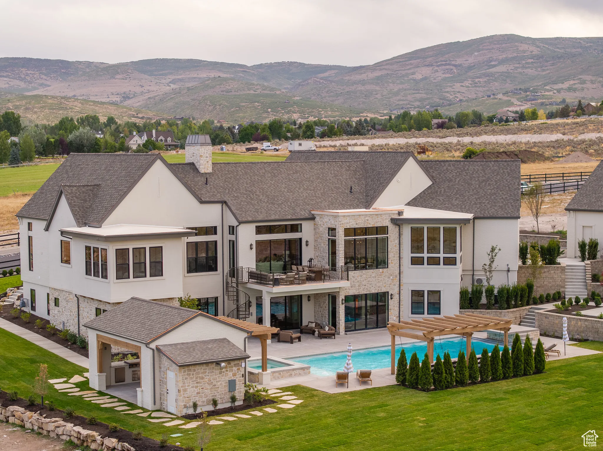 Back of property with a patio area, stucco siding, stone siding, a chimney, and a pool with connected hot tub