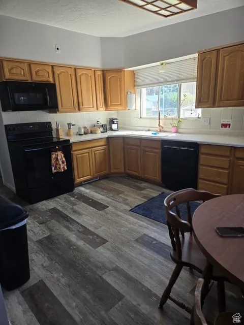 Kitchen featuring a textured ceiling, black appliances, light countertops, and brown cabinets
