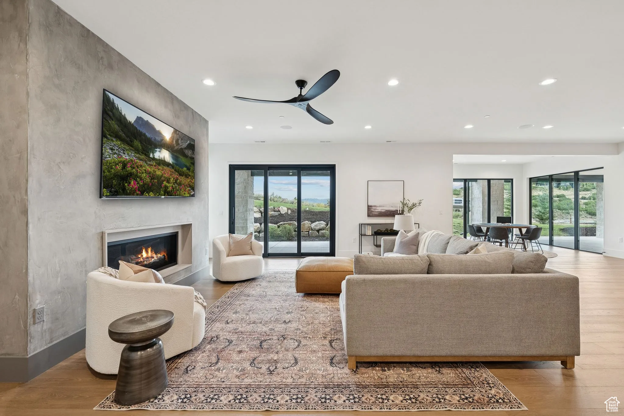 Living area featuring light wood finished floors, recessed lighting, a glass covered fireplace, and a ceiling fan