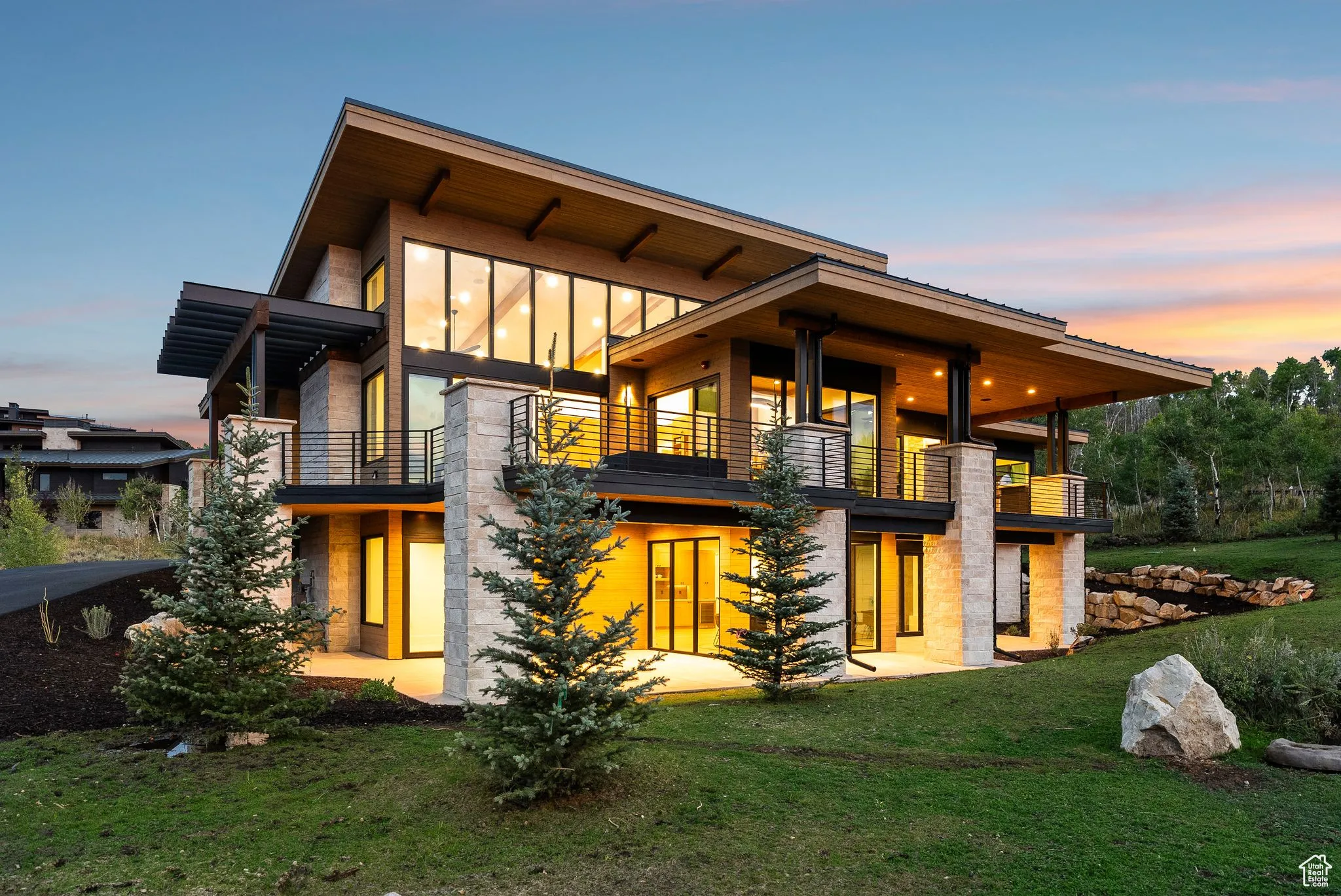 Back of property at dusk featuring a lawn and a balcony