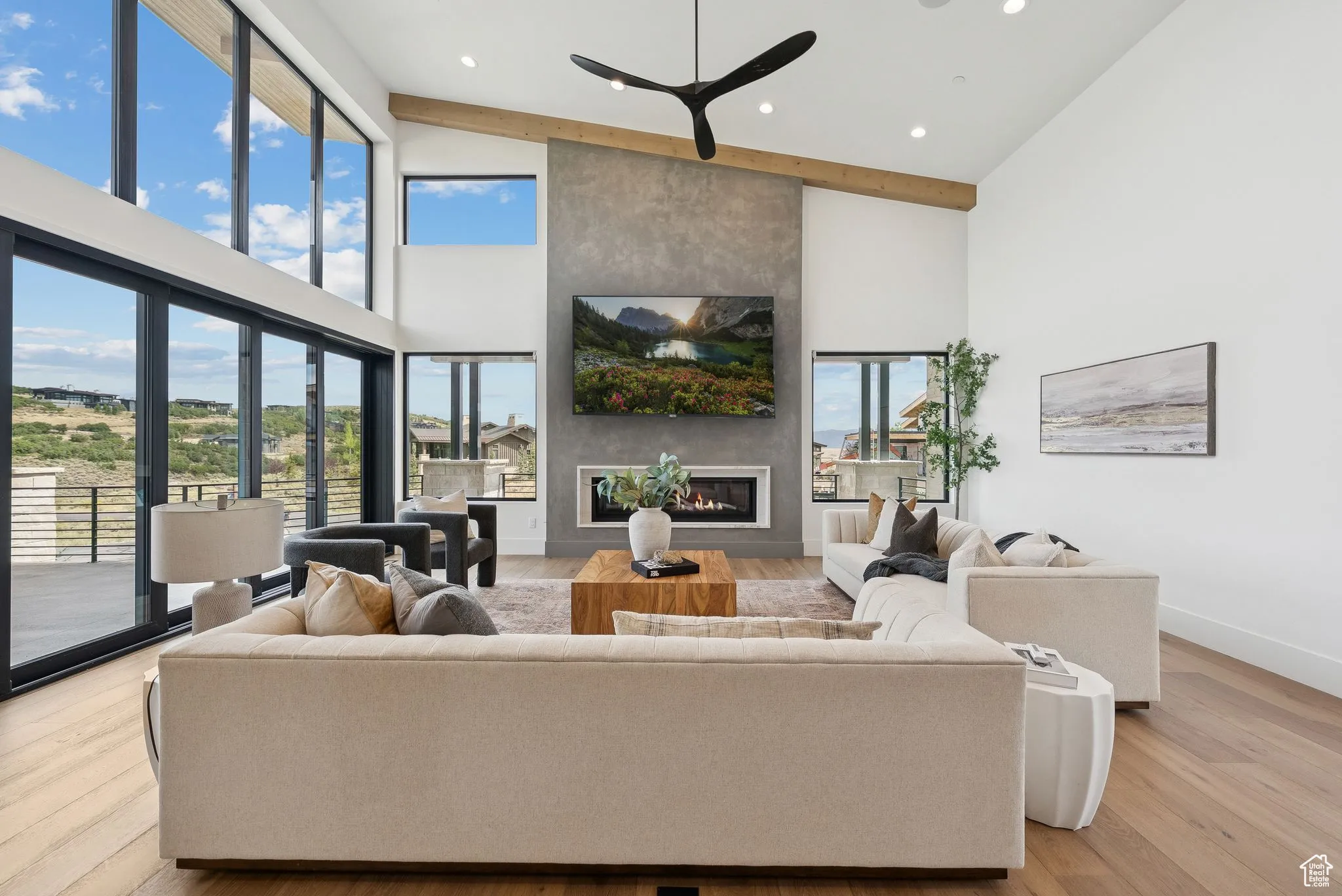 Living area featuring a large fireplace, light wood-style flooring, high vaulted ceiling, and recessed lighting