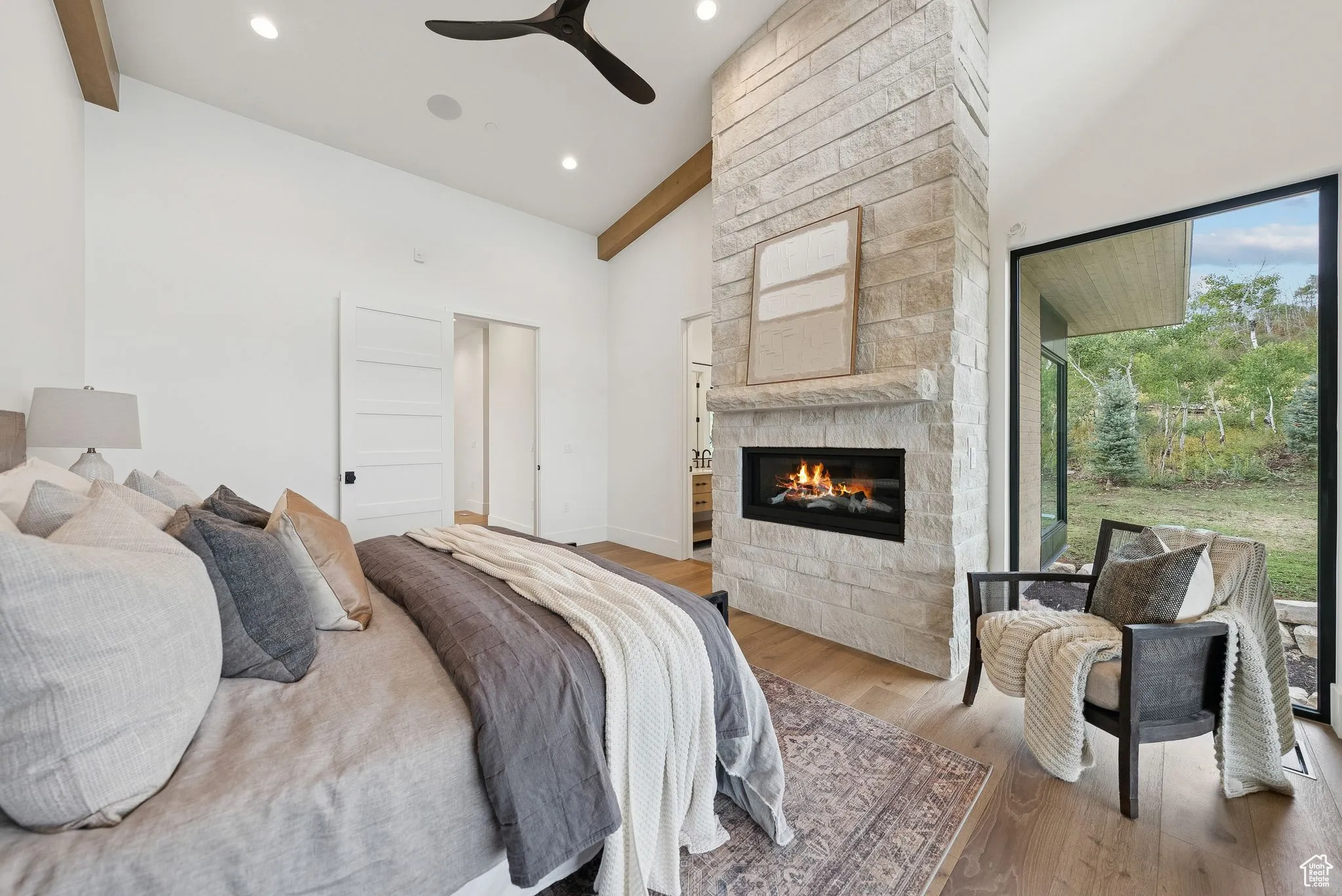 Bedroom with high vaulted ceiling, wood finished floors, beam ceiling, a fireplace, and ceiling fan