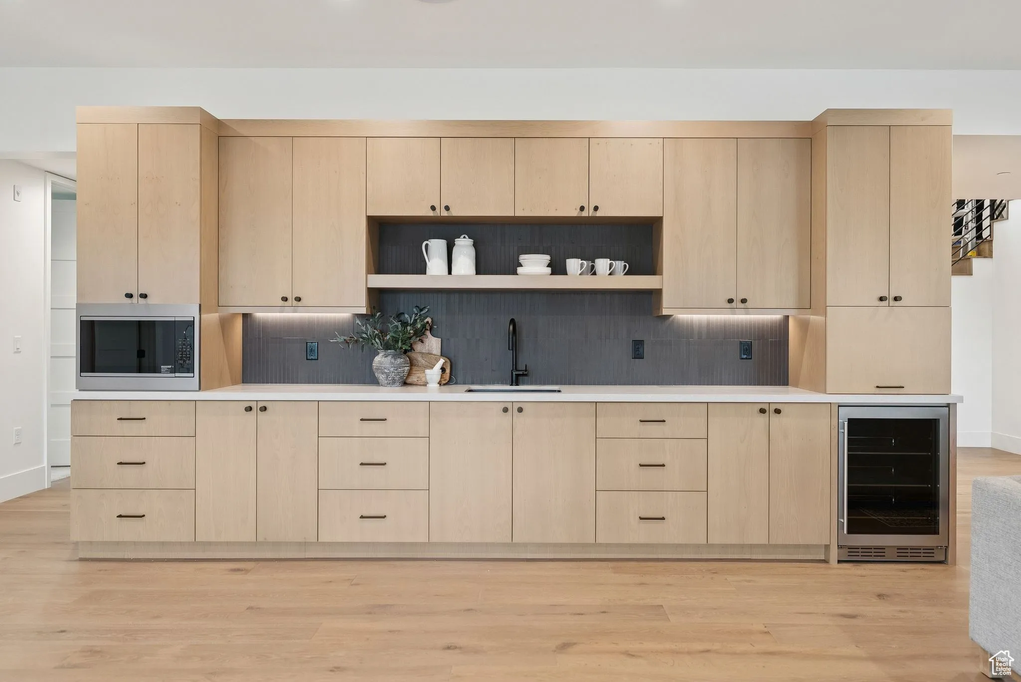 Kitchen featuring light brown cabinetry, open shelves, wine cooler, and light wood-type flooring