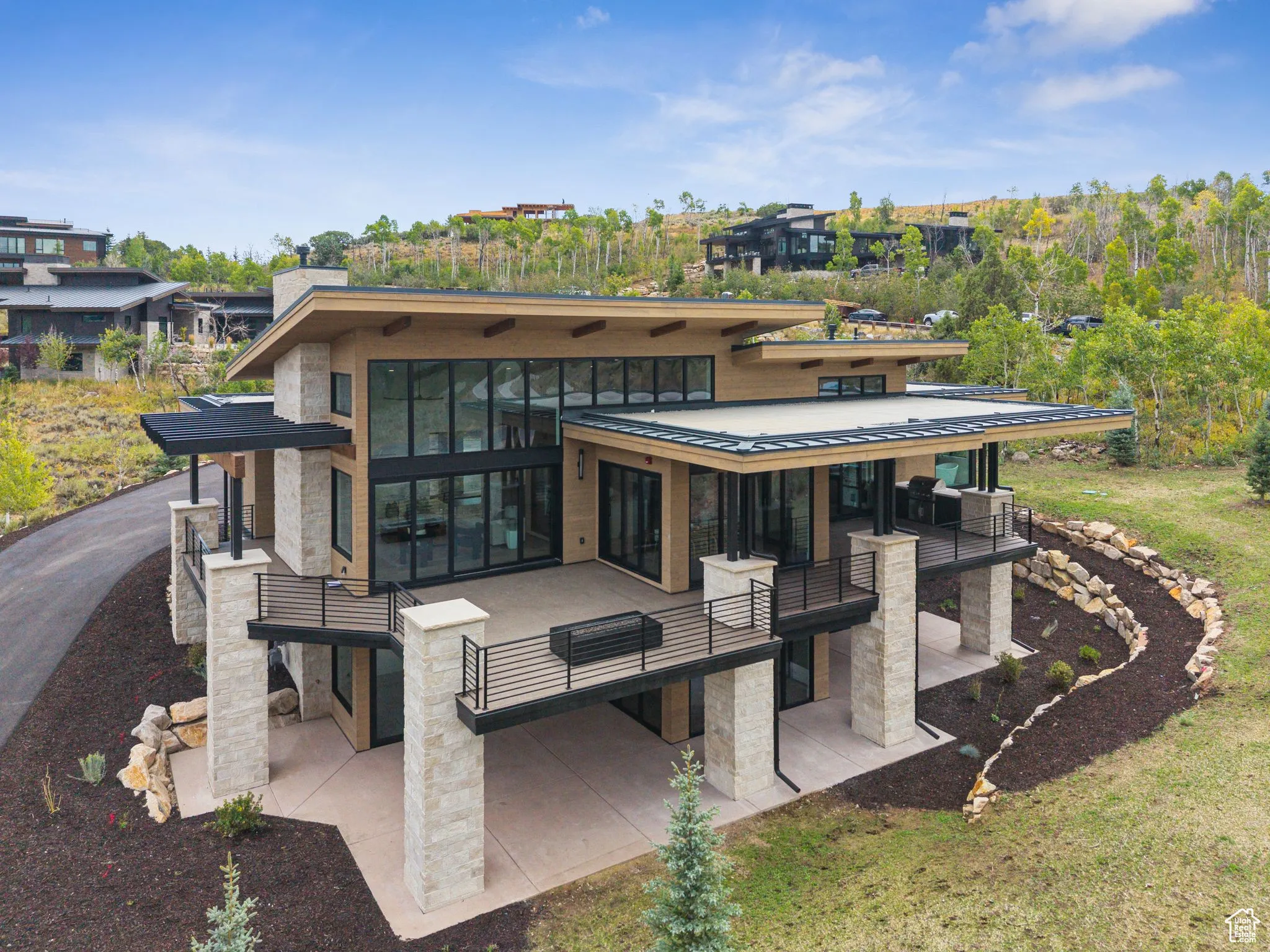 Back of house with a patio, stone siding, a standing seam roof, a metal roof, and a balcony