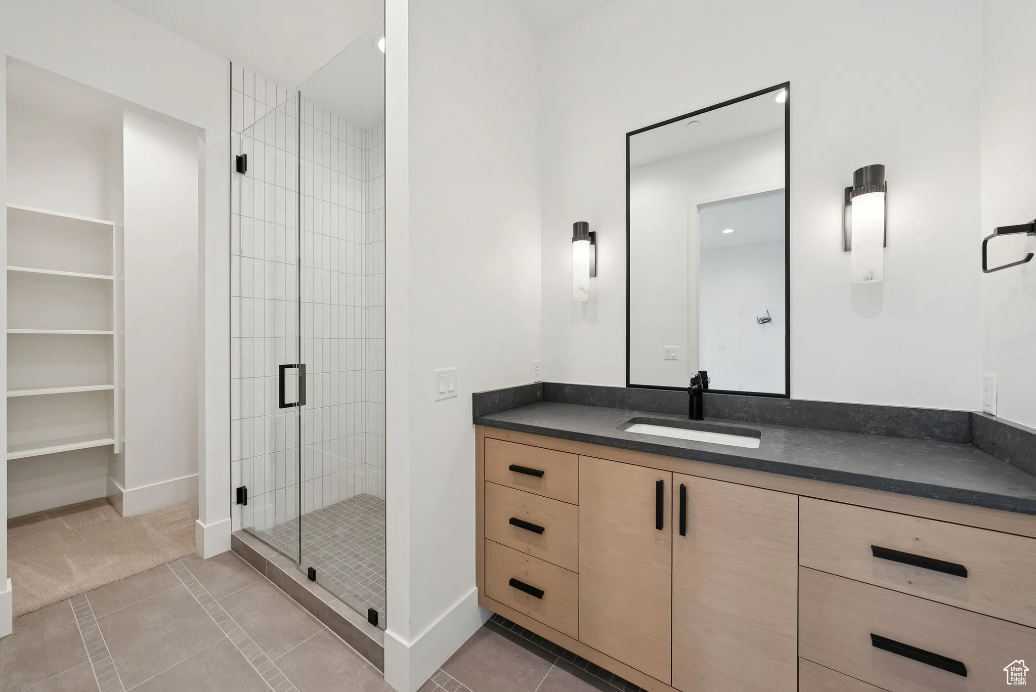 Full bath featuring light tile patterned floors, vanity, a stall shower, and a spacious closet