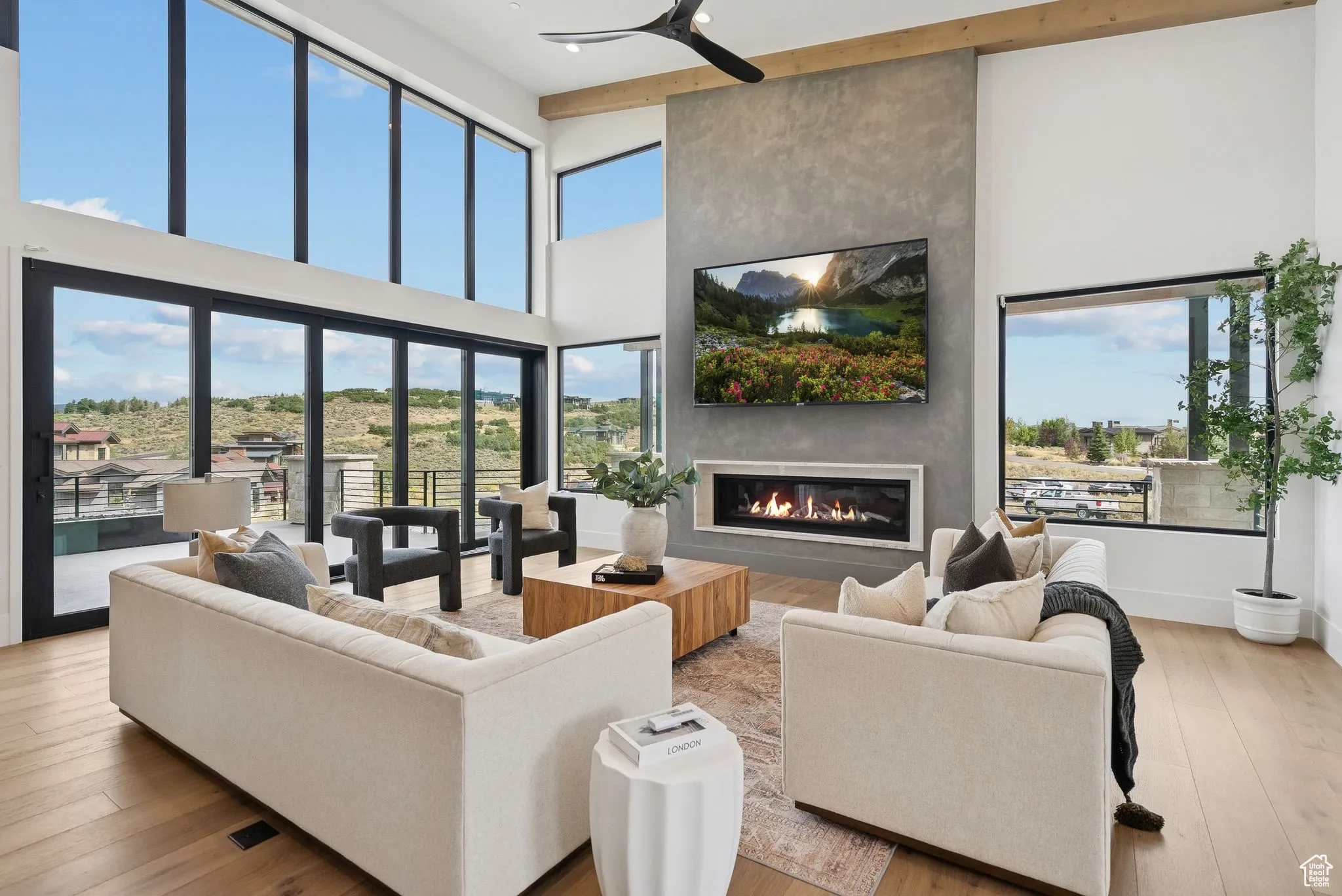 Living room with light wood finished floors, a fireplace, a towering ceiling, and a ceiling fan