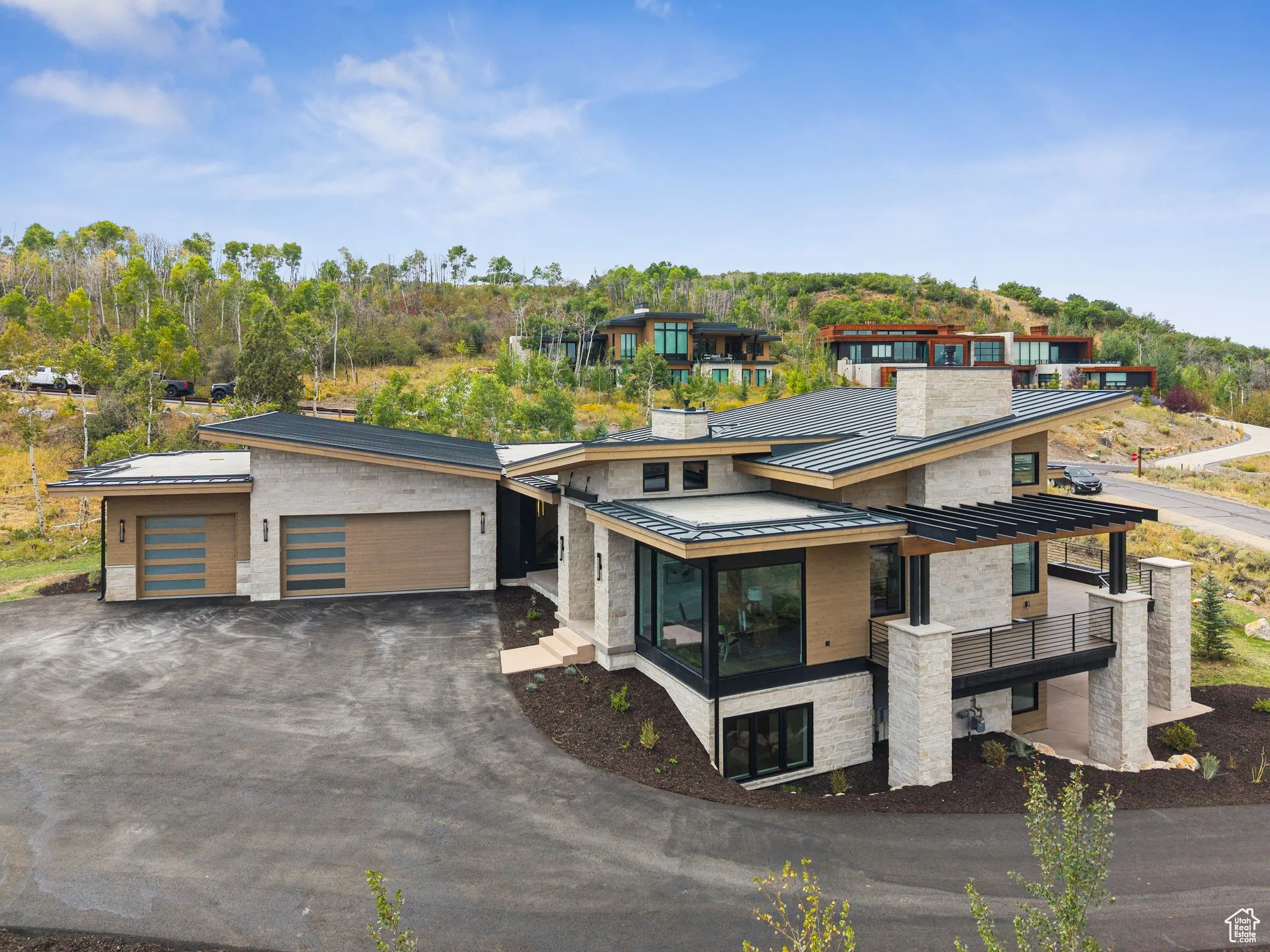 Contemporary house with a standing seam roof, a metal roof, asphalt driveway, an attached garage, and a sunroom