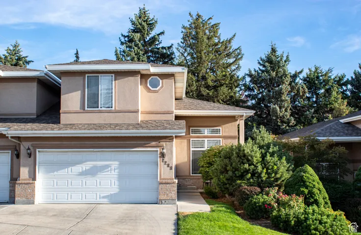 View of front of house featuring stucco siding, an attached garage, driveway, and a shingled roof