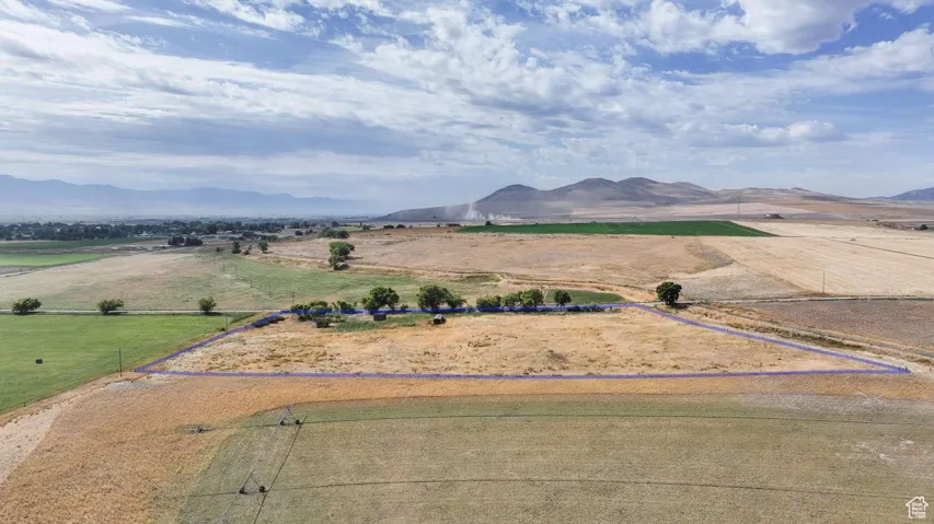 Aerial view of sparsely populated area featuring property boundaries highlighted and a mountainous background