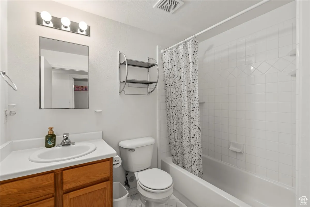 Full bathroom featuring shower / bathtub combination with curtain, vanity, and tile patterned floors