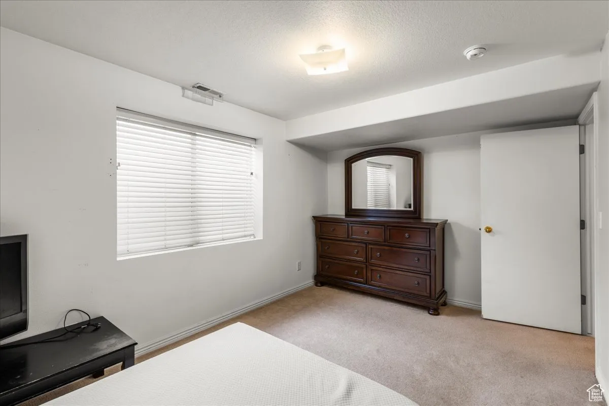 Bedroom featuring light colored carpet and a textured ceiling