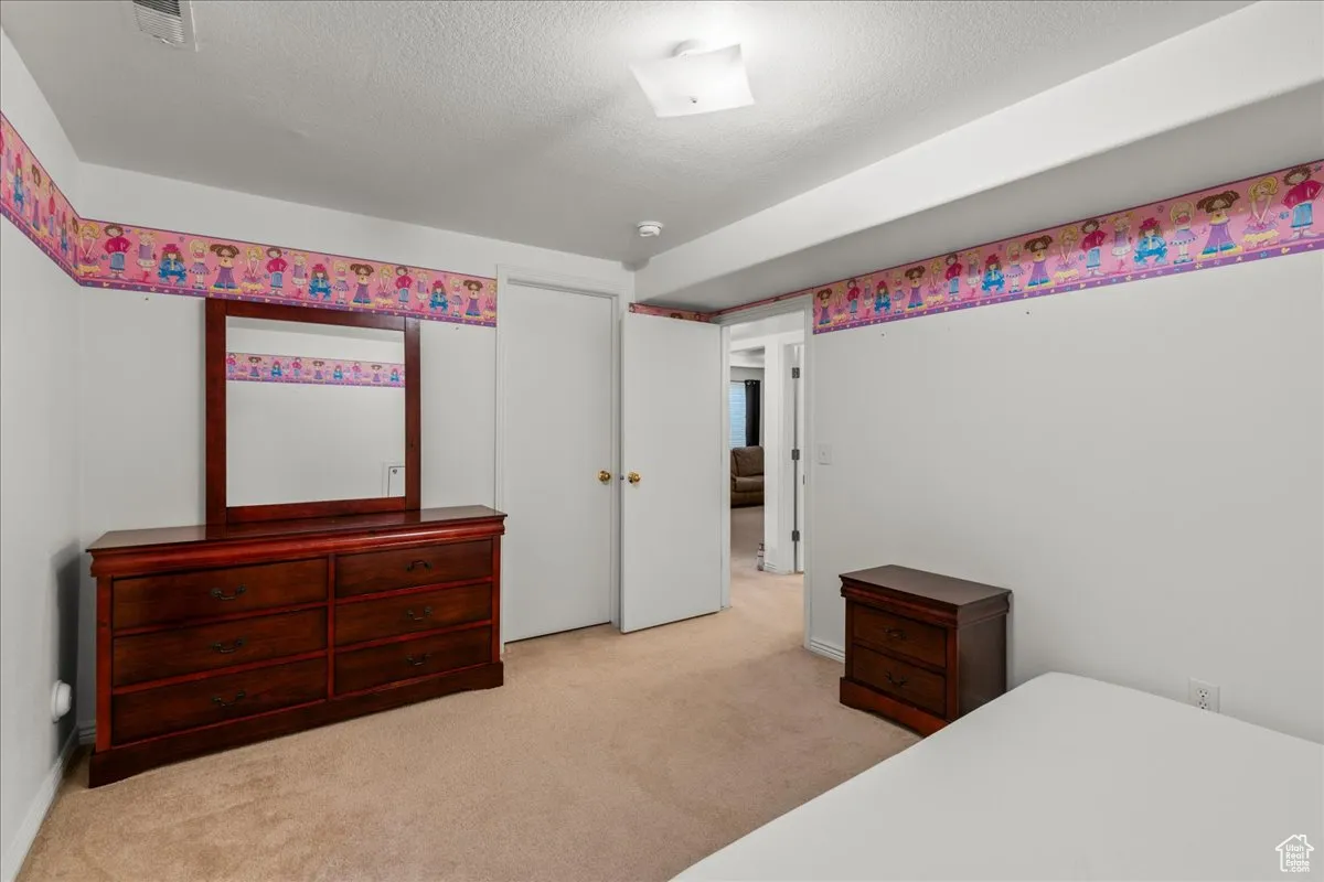 Bedroom featuring light carpet and a textured ceiling