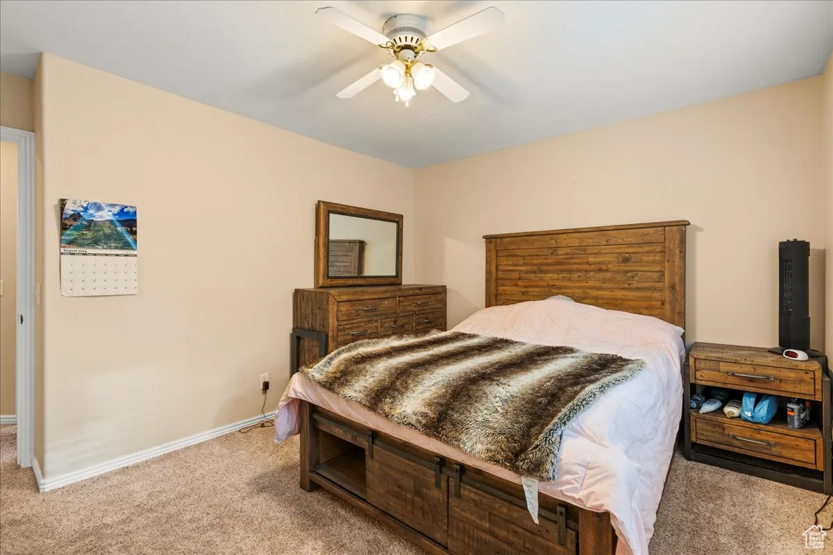 Carpeted bedroom featuring baseboards and a ceiling fan
