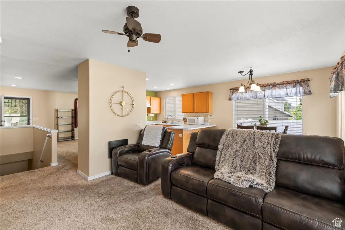 Living room featuring light colored carpet and a ceiling fan