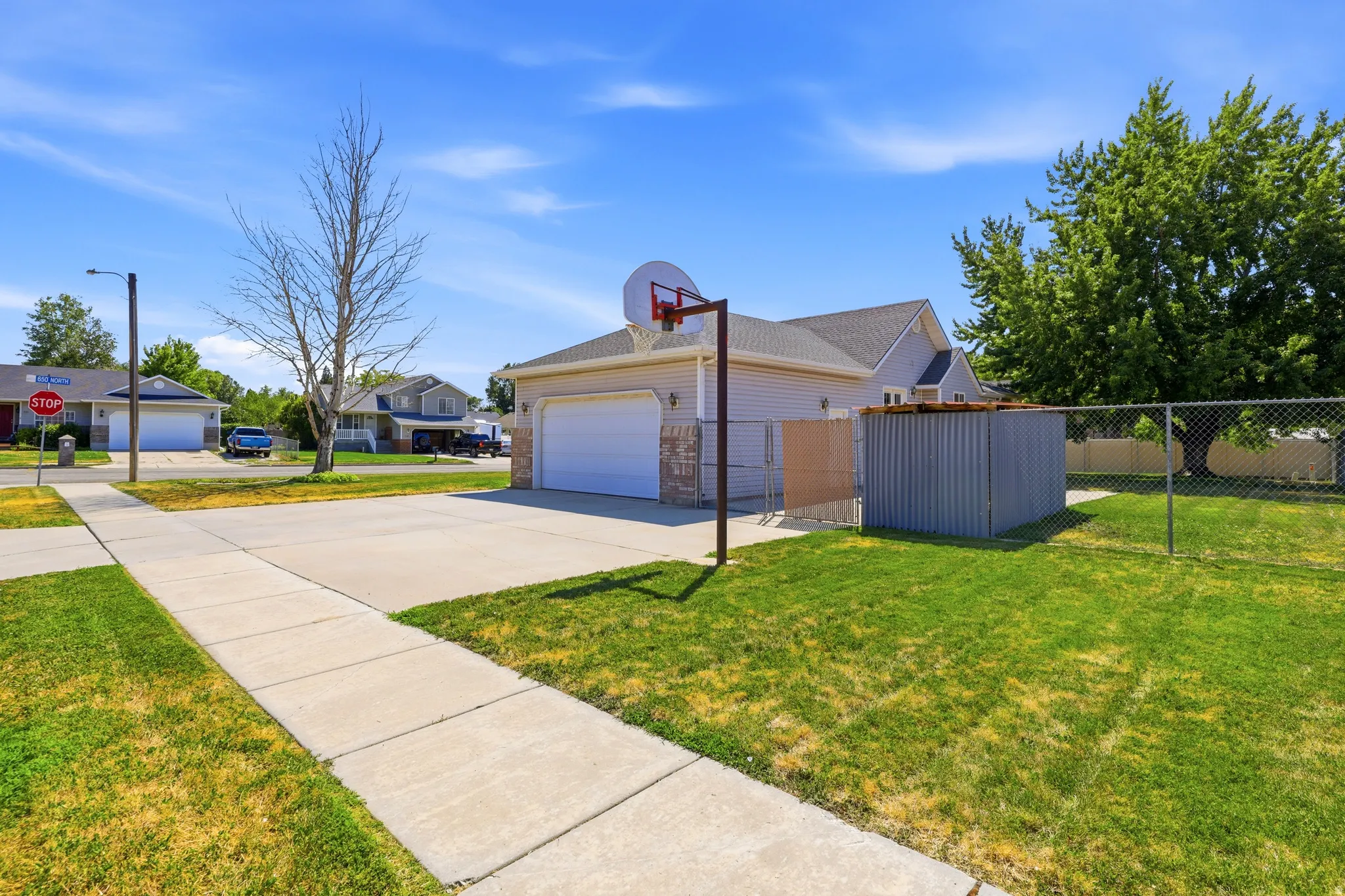 Attached two-car garage with a large concrete driveway, featuring a basketball hoop