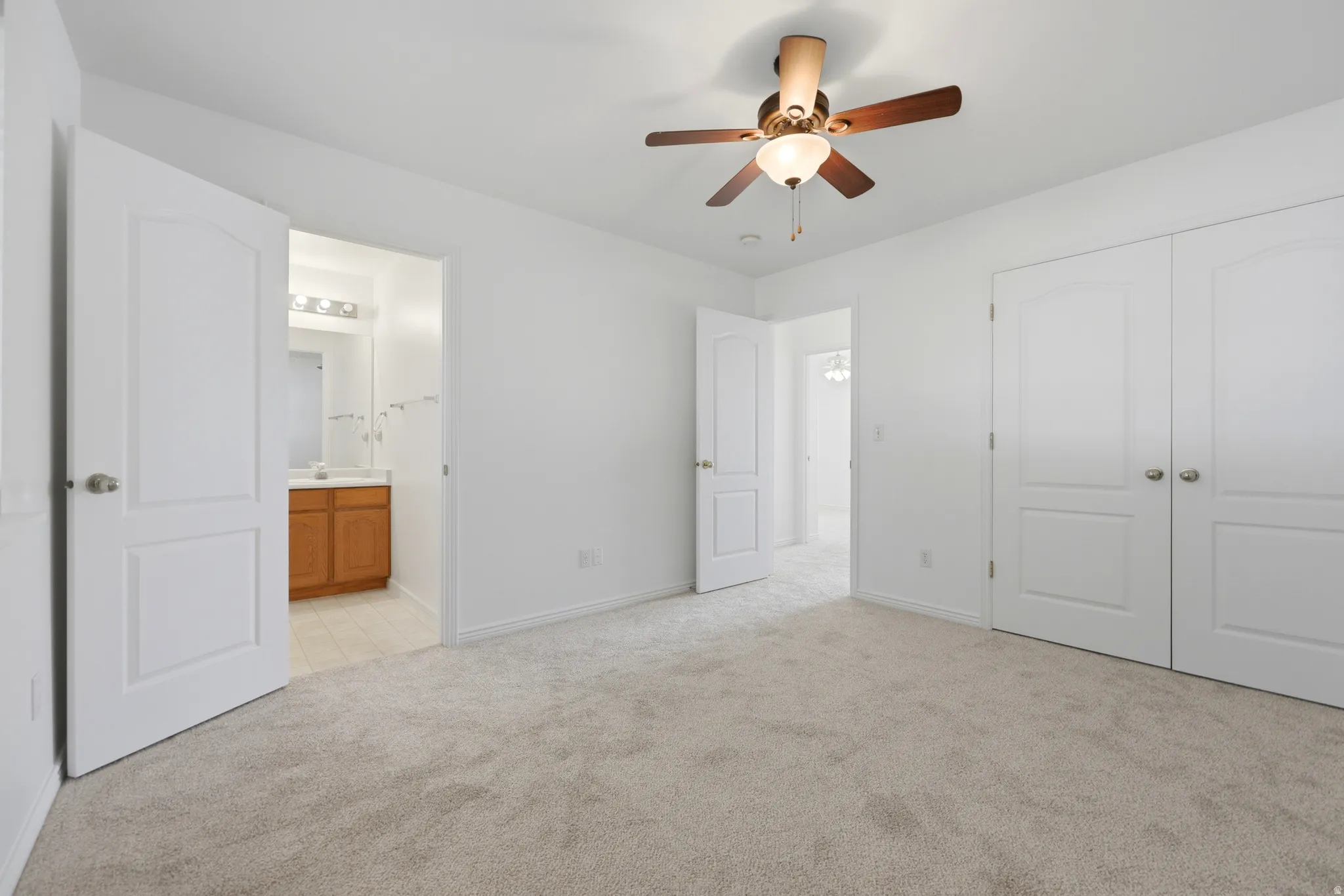 Carpeted room with white walls, featuring a ceiling fan with light fixture