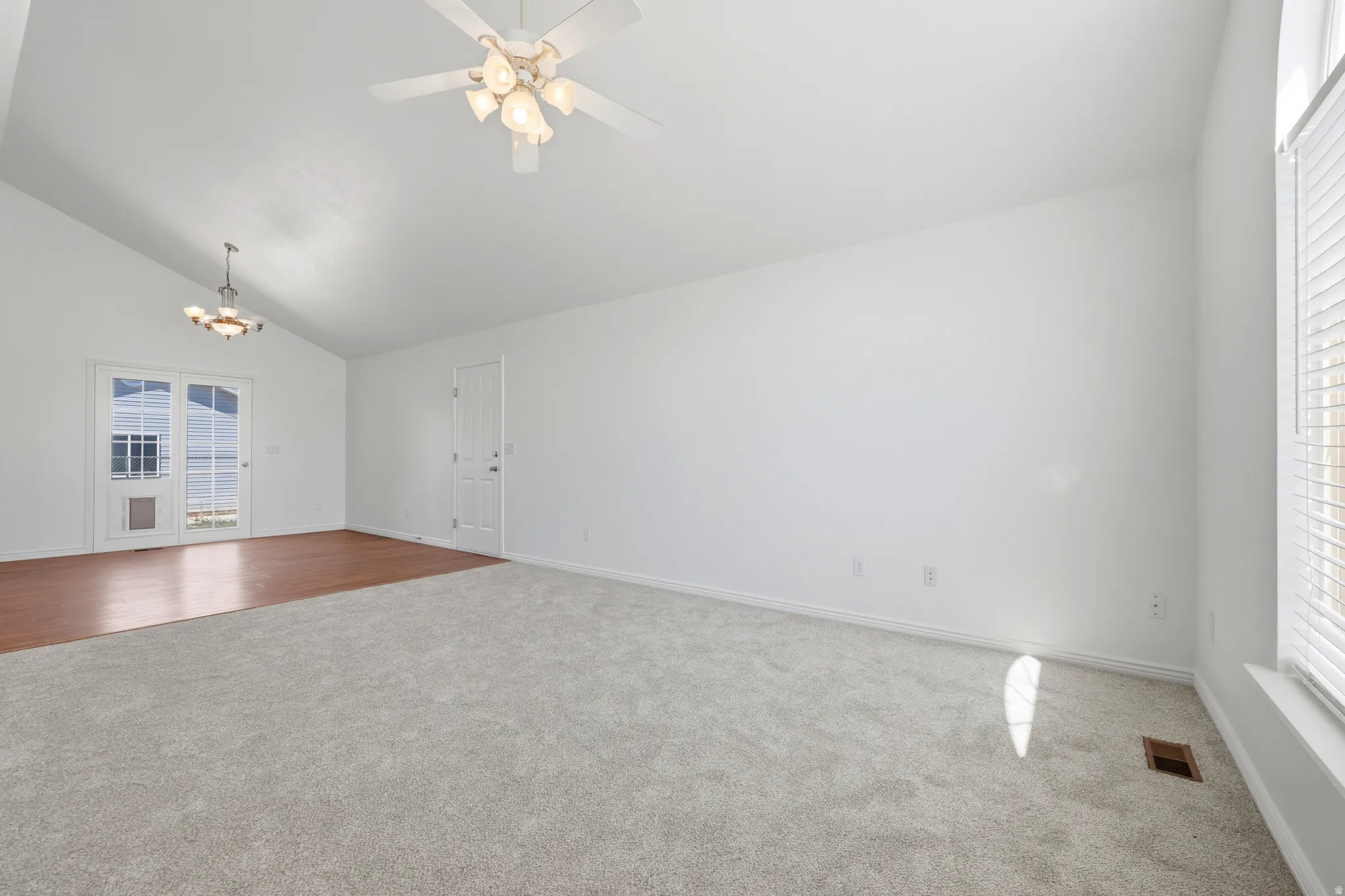 Spacious living area featuring a vaulted ceiling and a ceiling fan with light fixture