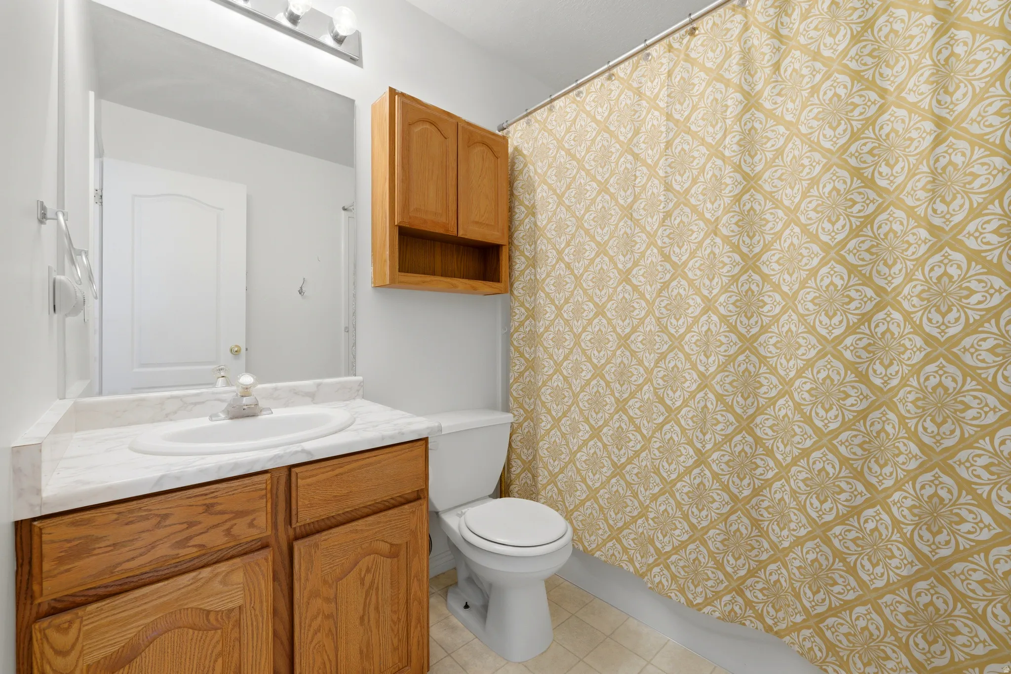 Full bathroom featuring a single vanity with wood-finish cabinetry, a white countertop, and an integrated sink