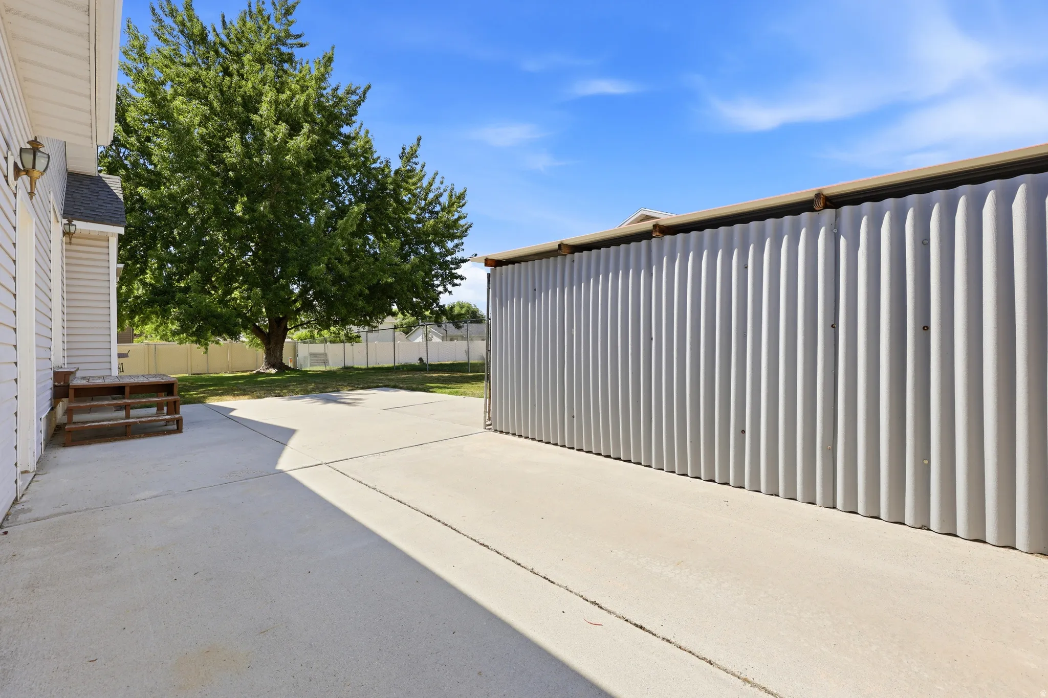 Expansive concrete patio area featuring a detached corrugated metal outbuilding