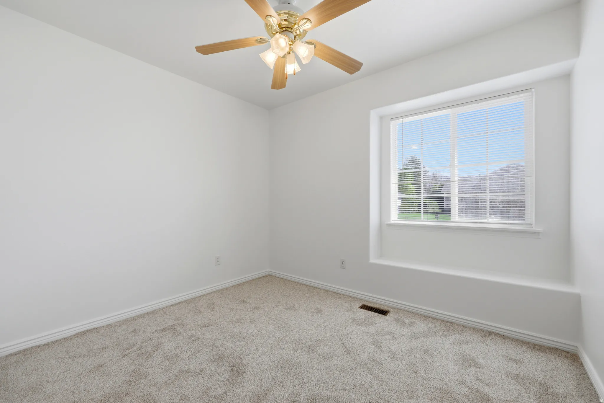Carpeted room with a large window, a built-in window seat, and a ceiling fan with light fixture