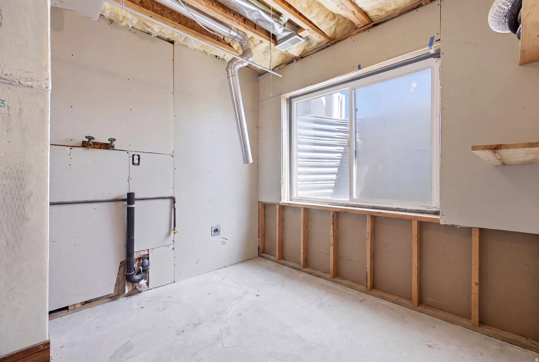 Unfinished interior space featuring a window, visible structural framing, exposed plumbing, exposed ductwork, and an unfinished ceiling
