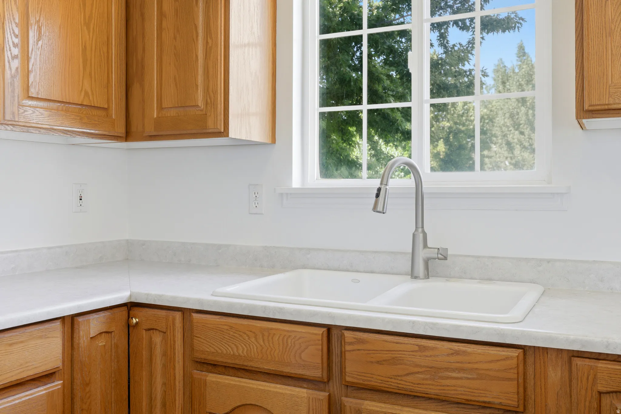 Kitchen window with white trim, a double basin sink, and a brushed nickel pull-down faucet