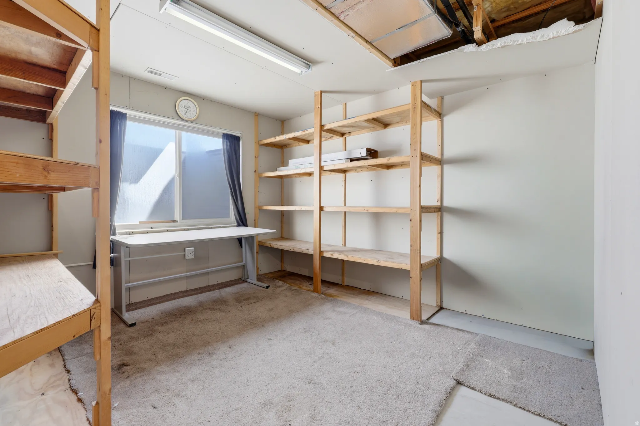 Spacious room featuring a large window, built-in wooden shelving, and a fluorescent ceiling light