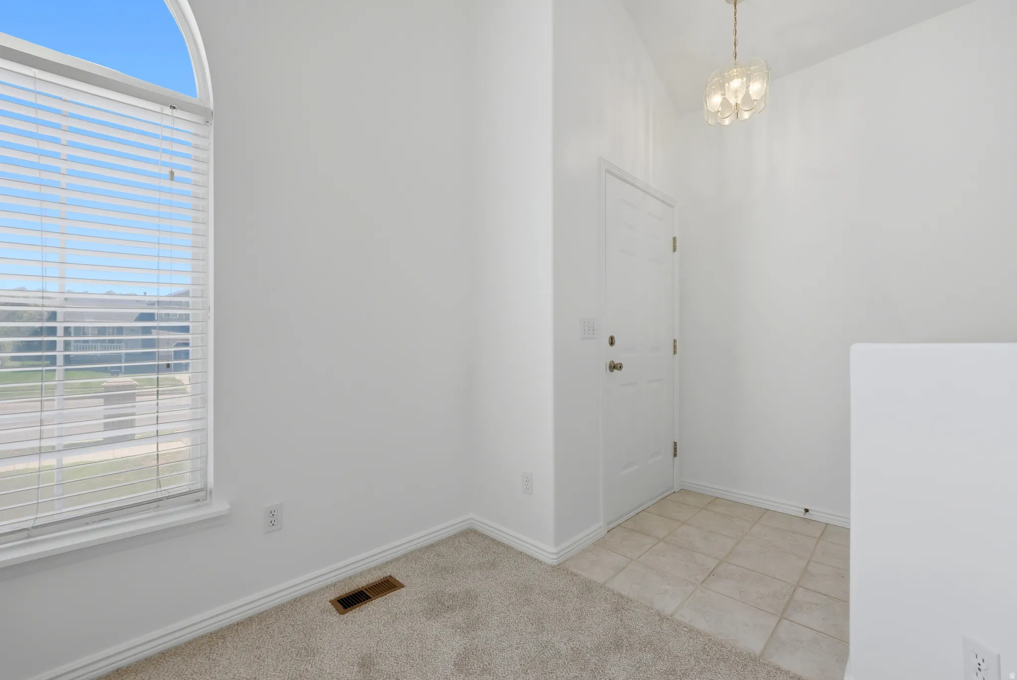 Entryway featuring a vaulted ceiling and a contemporary chandelier
