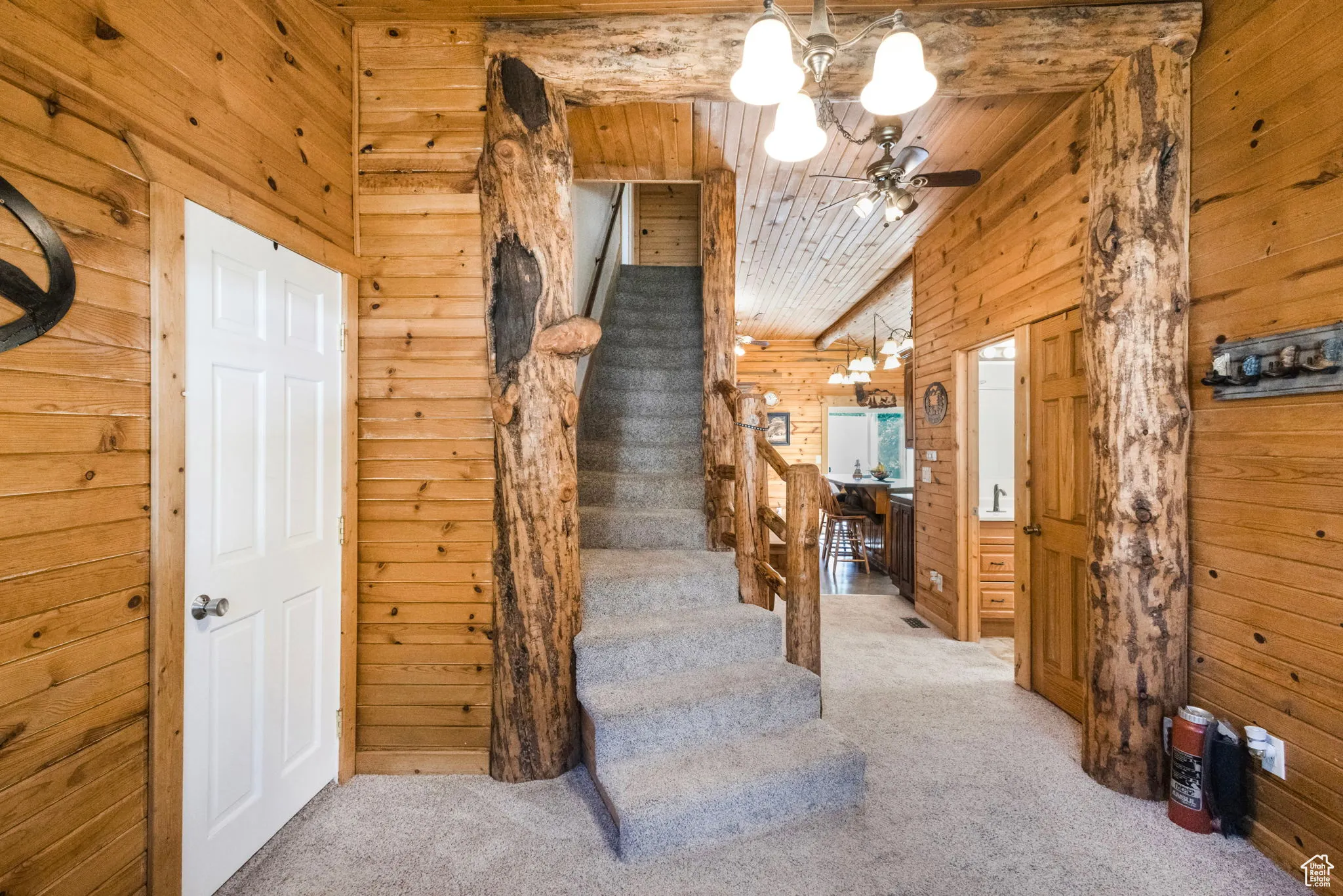 Stairs with wood walls, carpet, wooden ceiling, and a chandelier
