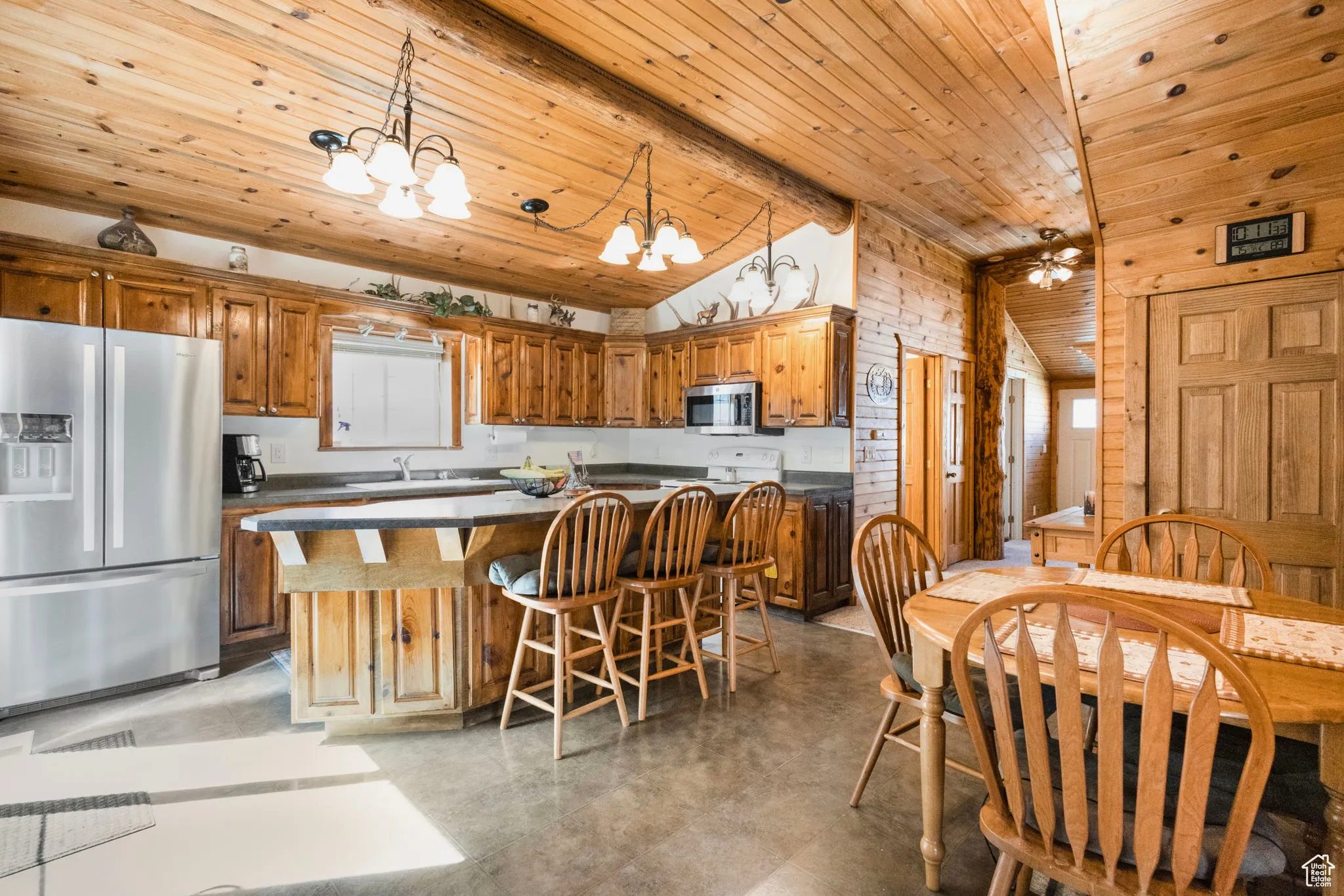 Kitchen featuring dark countertops, appliances with stainless steel finishes, a kitchen island, hanging light fixtures, and a chandelier