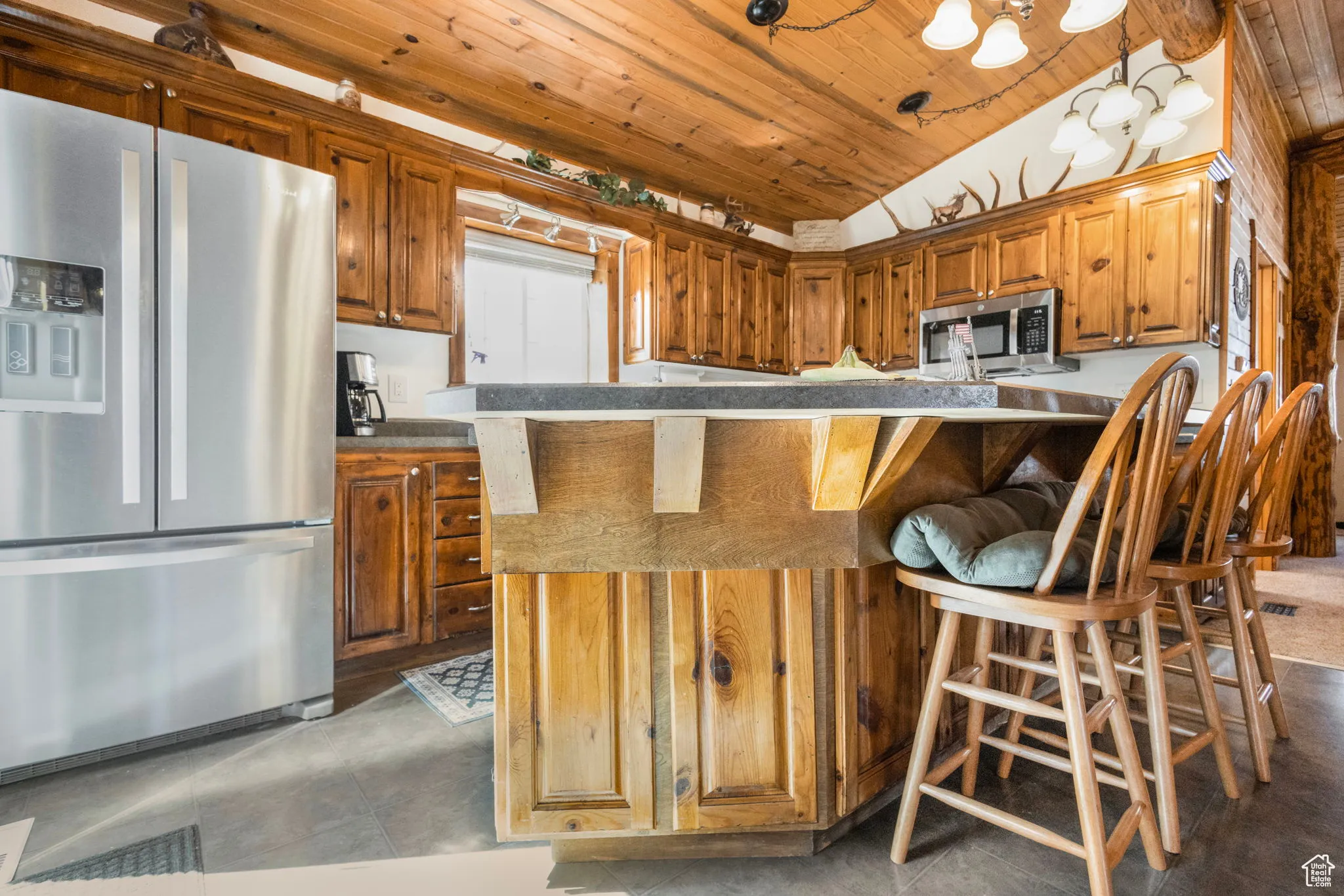 Kitchen featuring a breakfast bar, stainless steel appliances, lofted ceiling, wooden ceiling, and dark countertops