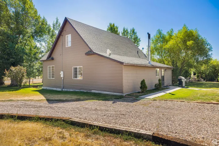 View of side of home with a yard and a shingled roof
