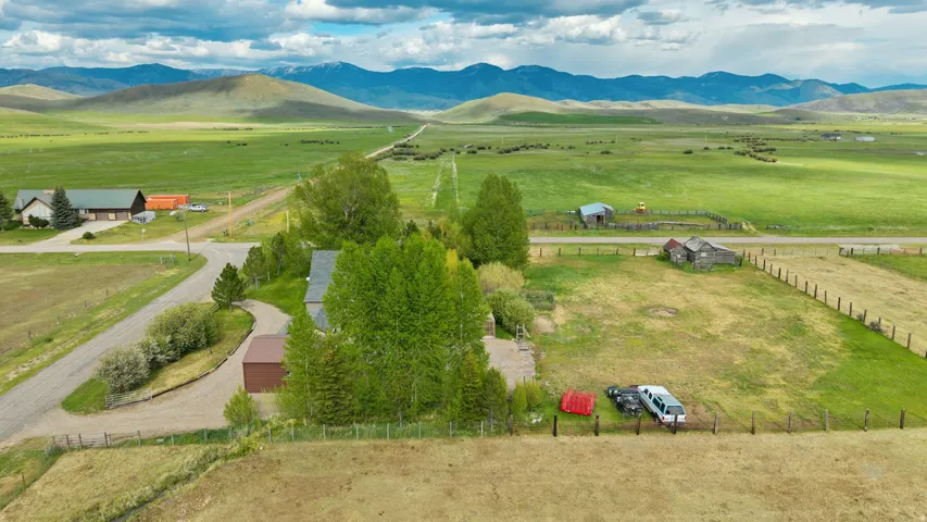 Expansive rural property featuring a main residence, a detached garage, and a fenced pasture area