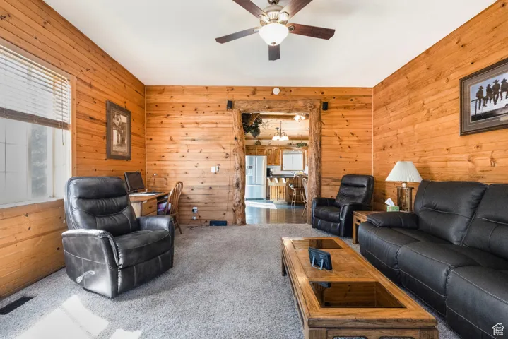 Carpeted living area featuring wooden walls and ceiling fan