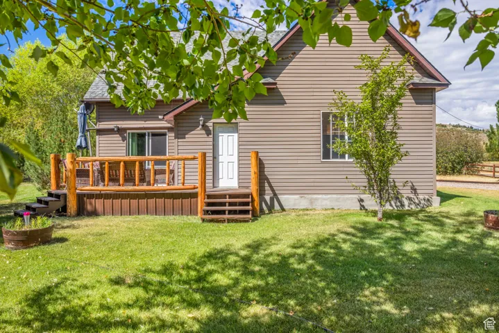 Rear view of house featuring a lawn and a deck
