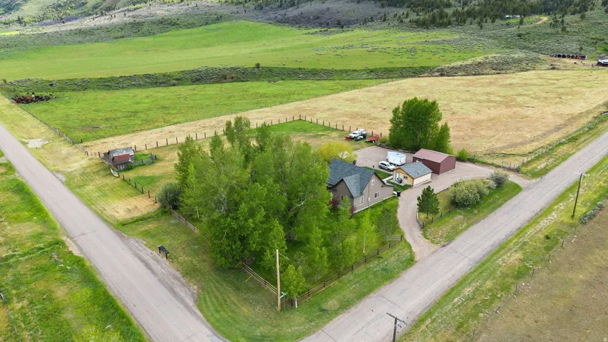 Expansive property featuring a residence with a dark shingle roof, surrounded by mature trees