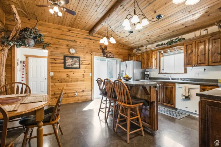 Kitchen featuring a breakfast bar area, wooden walls, a kitchen island, dishwasher, and stainless steel fridge