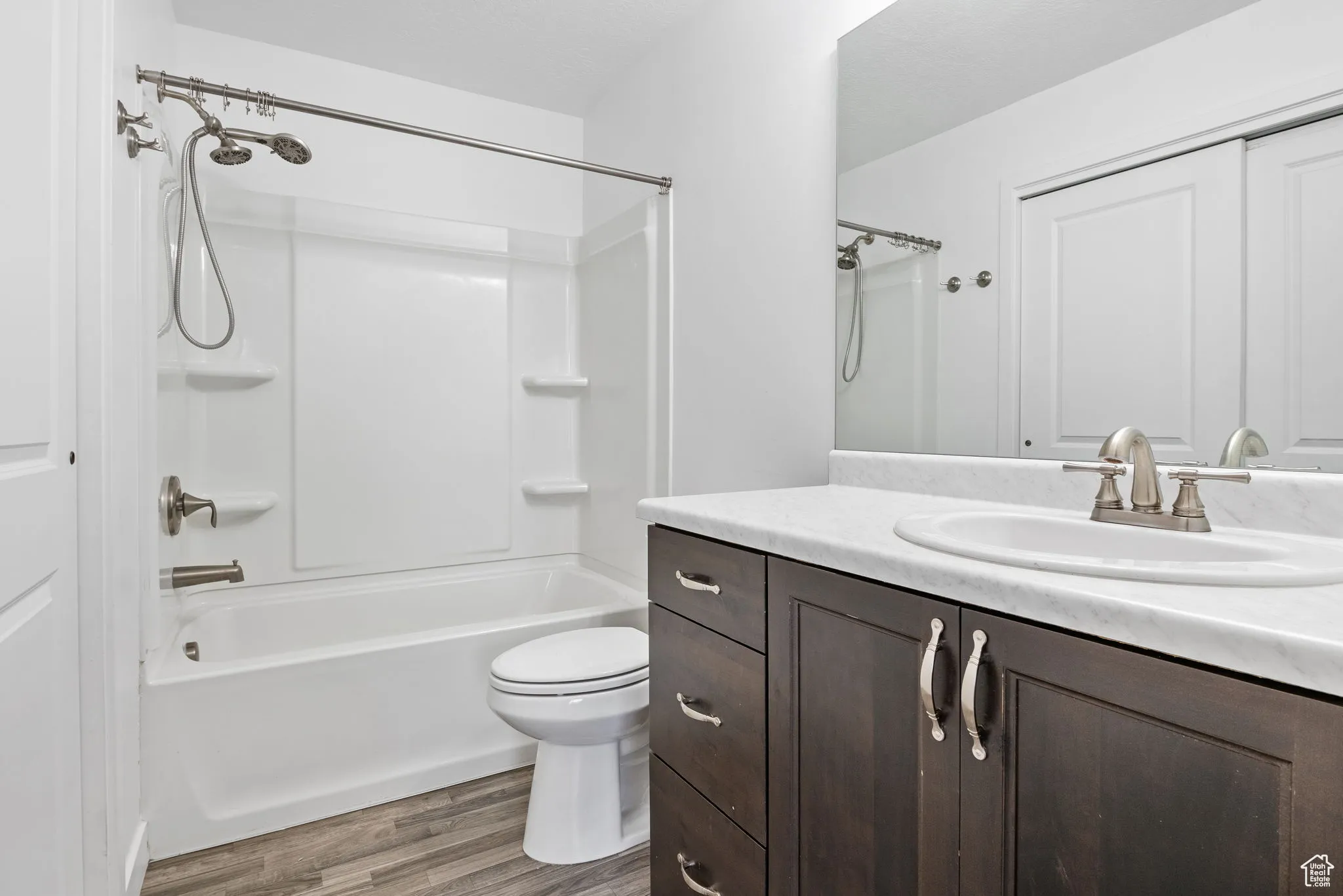 Full bath with washtub / shower combination, vanity, and dark wood finished floors