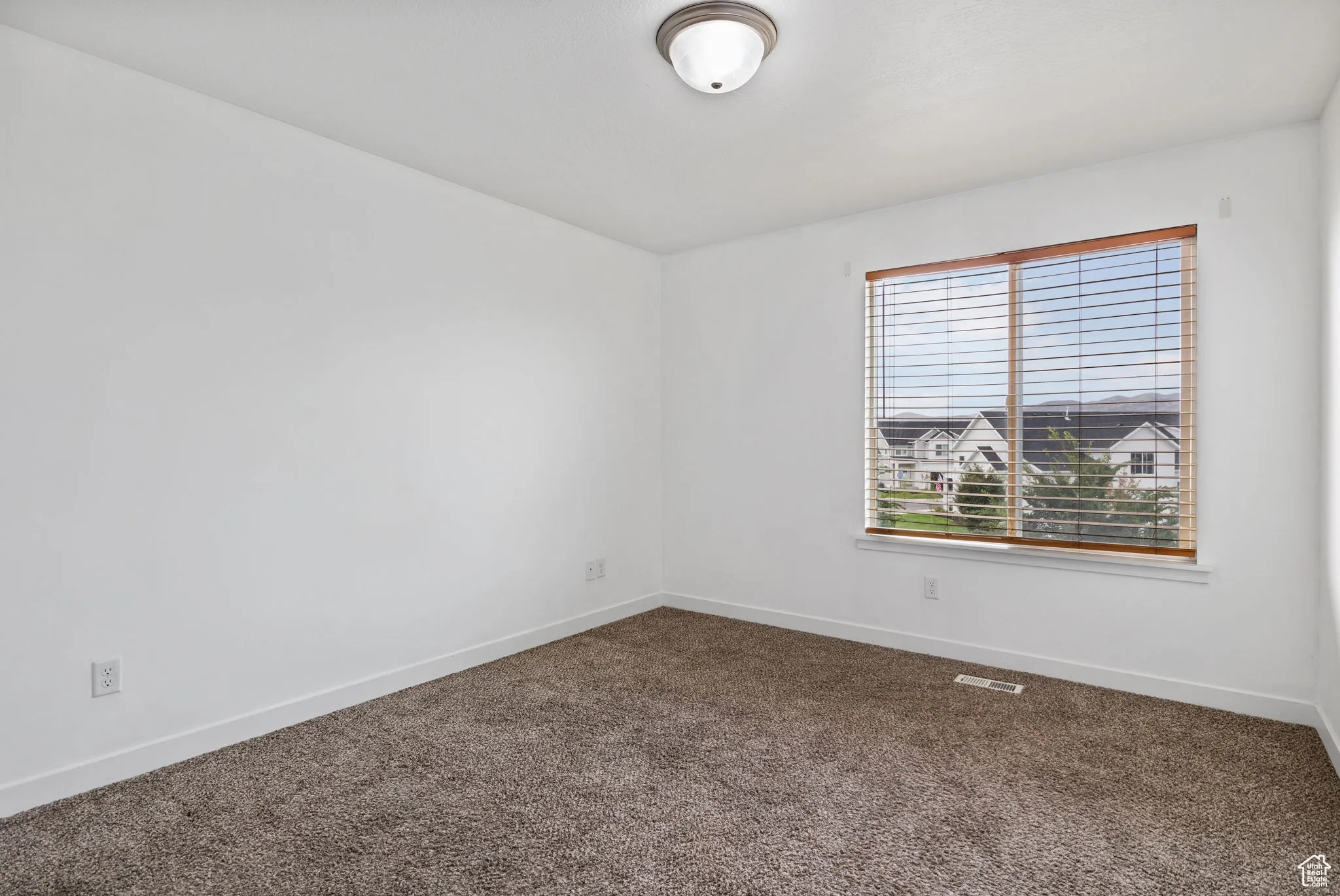 Spare room featuring dark colored carpet and baseboards