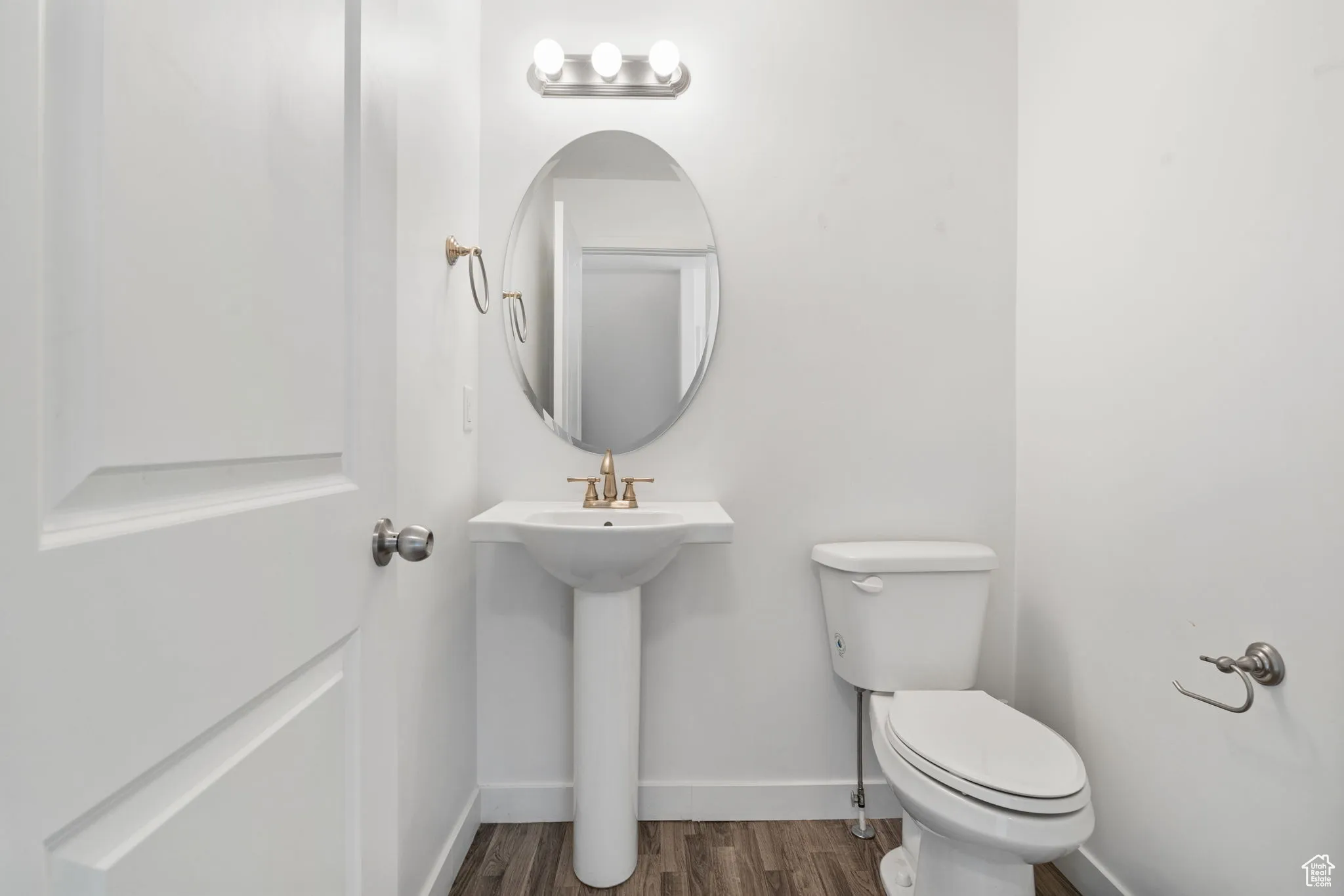 Half bathroom featuring toilet and dark wood-type flooring